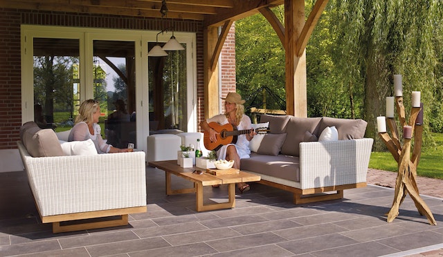 Two landlords relax on outdoor couches on a patio one property owner plays guitar as the other listens